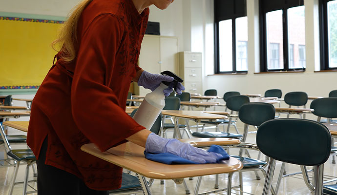 A person is cleaning furniture of a classroom