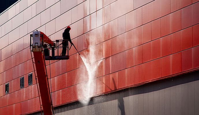 Building exterior pressure washing from boom lift
