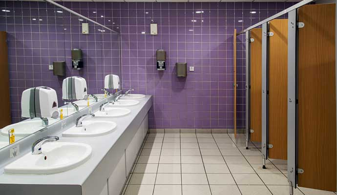 Clean commercial restroom with purple tiled walls and multiple sinks after odor control service