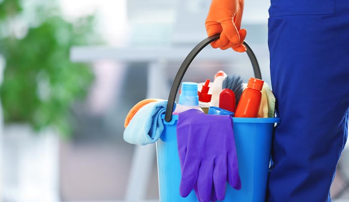 Cleaner holding a bucket of cleaning supplies