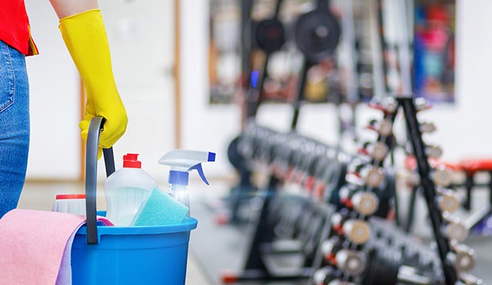 Cleaner holding cleaning equipments on bucket in gym
