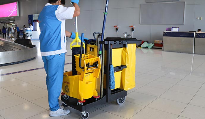 Professional janitor with cleaning cart
