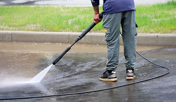 Expert cleaning concrete pavement with pressure washer