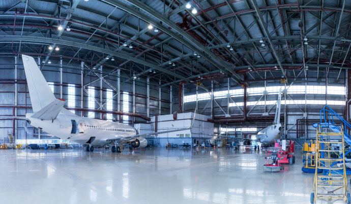 A wide interior view of a aviation hangar housing with two commercial aircraft