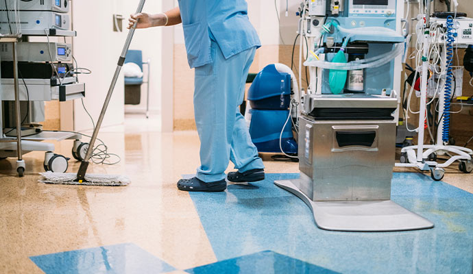 Person cleaning the floor of a medical facility.