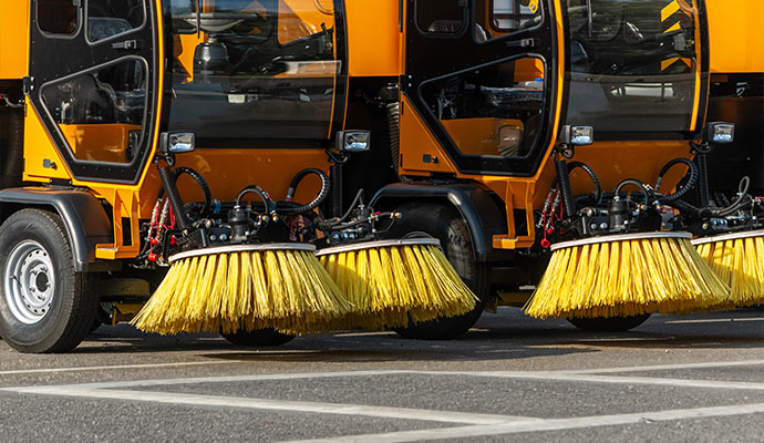 Parking lot sweeper vehicles cleaning a parking lot