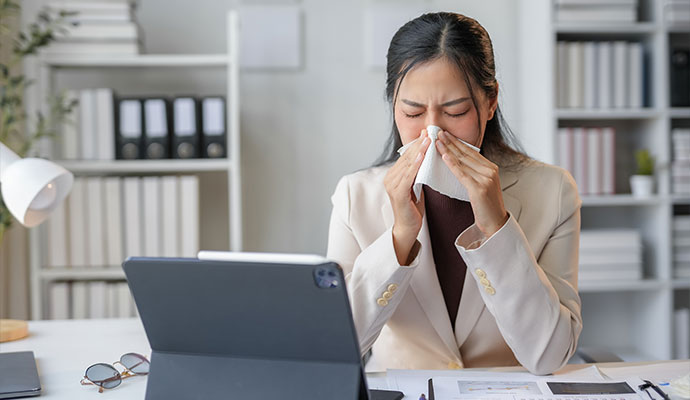 Woman sneezing at her office desk