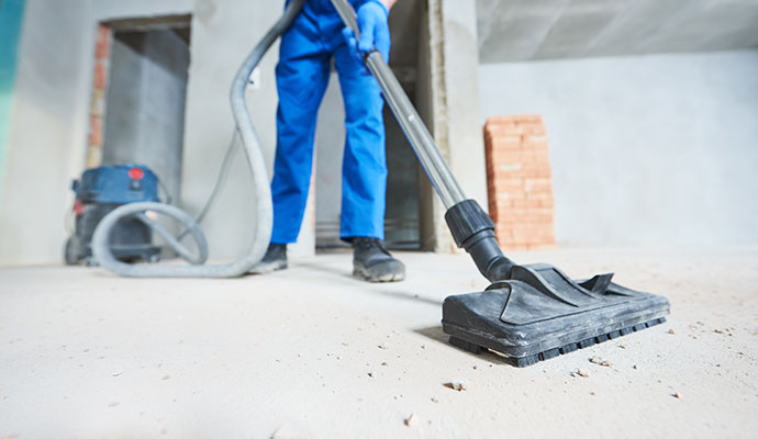 An expert cleaning dust and debris from a construction site floor