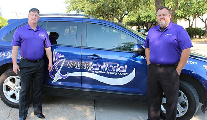 Two cleaning experts standing beside a Valor Janitorial service vehicle