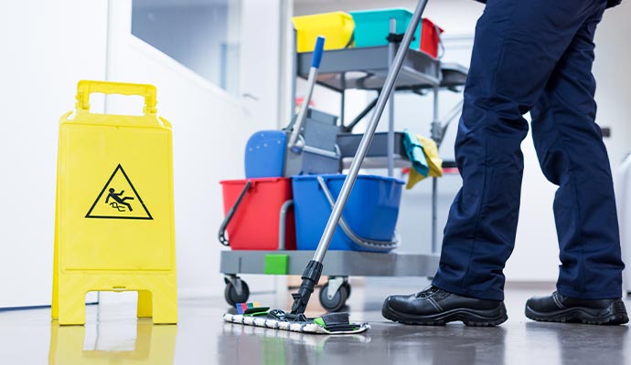 Janitor mopping a floor next to a wet floor