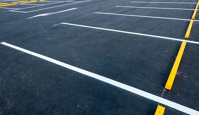 parking lot with crisp white stall lines and bright yellow wheel curb blocks