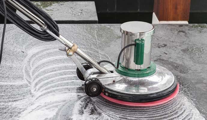 Person cleaning stone floor with equipment