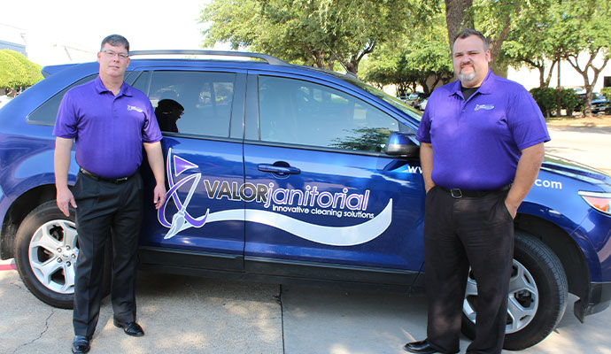 Valor Janitorial team members standing beside a service vehicle